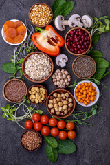 Superfood concept,  fresh vegetables and greens, seeds, grains  in wooden bowls  on black background. Top view