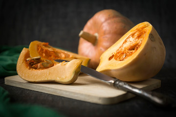 Beautiful ripe pumpkins against a dark background, sliced and whole.