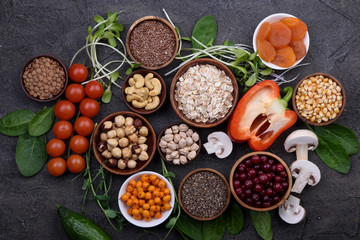 Superfood concept,  fresh vegetables and greens, seeds, grains  in wooden bowls  on black background. Top view