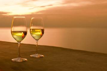 Pair of wine glasses on hotel balcony and beautiful ocean sunset view. 