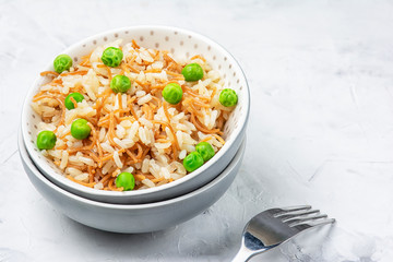 Turkish national side dish. A pilaf of rice and fried noodles decorated with green peas. Light photo with copy space.