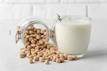 Dairy-free milk. Chickpea nut scattered on the surface in a glass jar and milk in a mug on a light background. Lactose free.