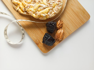 Puffed corn cakes, prunes and pecans on wooden curring board. Diet and healthy lifestyle for be fit for summer season.