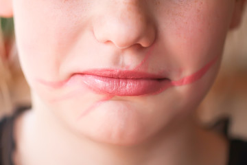 Obraz premium Young attractive teenager girl doing make-up. Lipstick smeared on the lips