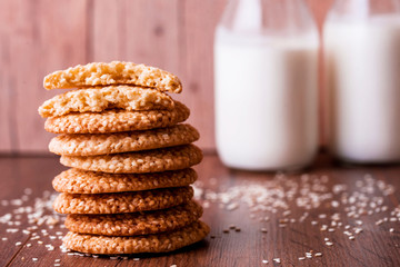 Round sesame cookies with milk and juice on the table.
