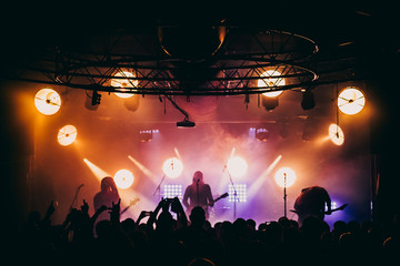 Metal band performing live on stage. Underground black metal gig. Stage lights shining behind...