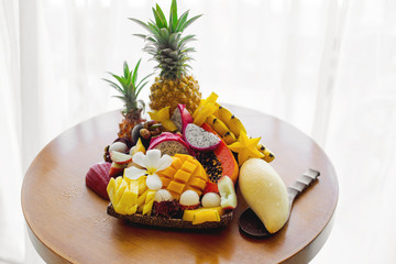 Juicy ripe tropical Thai fruits on a wooden dish.