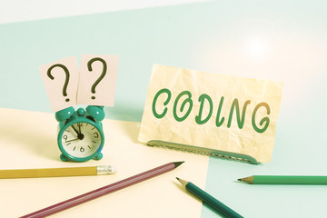 Word writing text Coding. Business photo showcasing assigning code to something for classification identification Mini size alarm clock beside stationary placed tilted on pastel backdrop