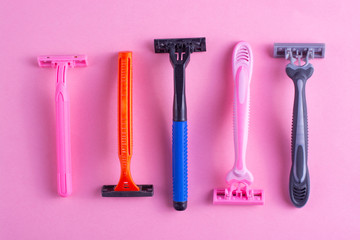 Colored plastic disposable razors on a pink background close-up.