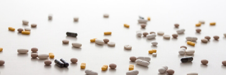 Scattered pills on a white background. Copy space. Nobody. Medicine. Panoramic photo
