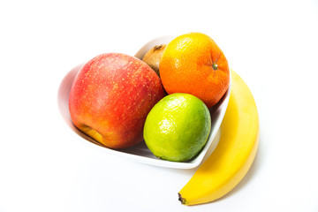 Heart-shaped bowl with fruit isolated on white background. The concept of healthy eating, eating fruit. Bowl with apple, mandarin banana. A bowl filled with fruit. Fruit and vitamins for the heart.