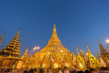 A lot of people in front of the gilded and illuminated Shwedagon Pagoda in Yangon, Myanmar, at dusk. Copy space.