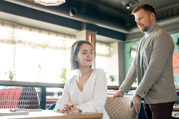Horizontal shot of modern gentleman paying adresses to young woman on date in restaurant