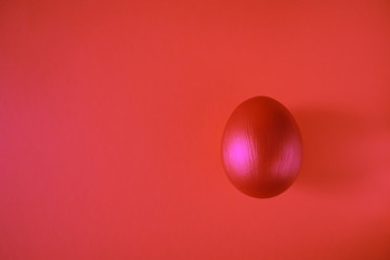 Red Easter egg on colorful red background. Happy Easter concept, copy space, top view.