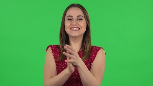 Portrait of tender girl in red dress is clapping her hands with wow happy joy and delight. Green screen