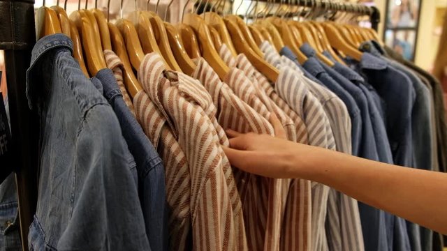 Hand of young woman shopper choosing cloth in department store