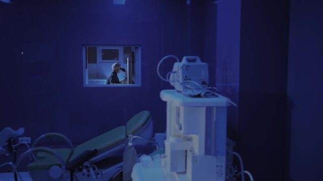 In a Modern Laboratory Scientist Conduct Experiments. Chief Research Scientist Adjusts Specimen in a Petri Dish and Looks on it Into Microscope.
