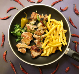 Grilled meat skewers with bacon, onion, peppers and chilli. Served with french fries.