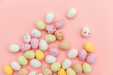 Happy Easter concept. Preparation for holiday. Easter candy chocolate eggs and jellybean sweets isolated on trendy pastel pink background. Simple minimalism flat lay top view copy space.