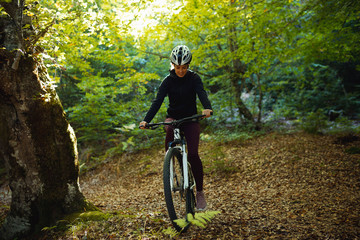 Fototapeta na wymiar Female cyclist riding mountain bike in forest