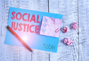 Conceptual hand writing showing Social Justice. Concept meaning Equal access to wealth and privileges within a society Wrinkle paper and cardboard placed above wooden background