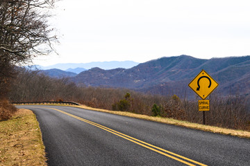 Yellow Spiral Curve Sign Along a Mountain Roadway