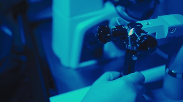In a Modern Laboratory Scientist Conduct Experiments. The embryologist Examines Samples with a Microscope, Close-up Hands