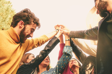 Group of multiracial young friends holding hands disposed in a circle. Young people enjoying life....