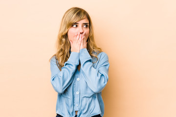 Young blonde caucasian woman thoughtful looking to a copy space covering mouth with hand.