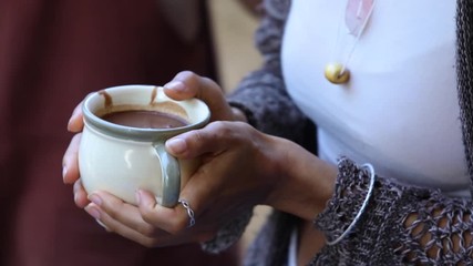 Closeup of male and female community of shamans taking their cups filled with melted chocolate refreshment from counter during guided cacao ceremony