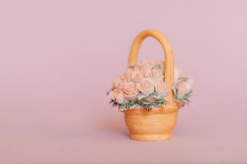 A bouquet of porcelain roses stands in a small basket on a wooden table on a black background. Copy space