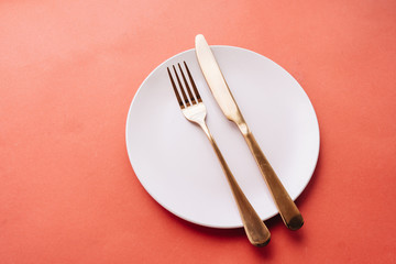 plate, fork, knife on red table, elegant tableware 
