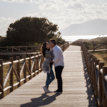 Pareja de novios bes&aacute;ndose en un camino de madera frente al mar