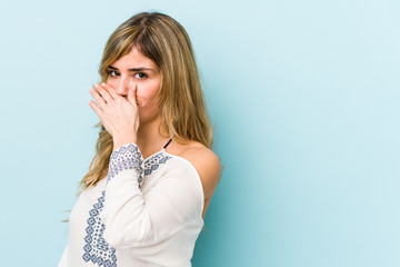 Young blonde caucasian woman covering mouth with hands looking worried.