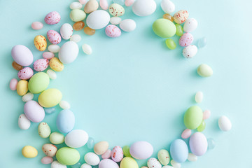 Happy Easter concept. Preparation for holiday. Easter candy chocolate eggs and jellybean sweets isolated on trendy pastel blue background. Simple minimalism flat lay top view copy space.