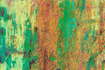 Part of old metal exterior doors. Yellow and green painted, in bouncing layers,  rusty surface with nail head in the evening sunlight. Bright multi-color texture. Space for text