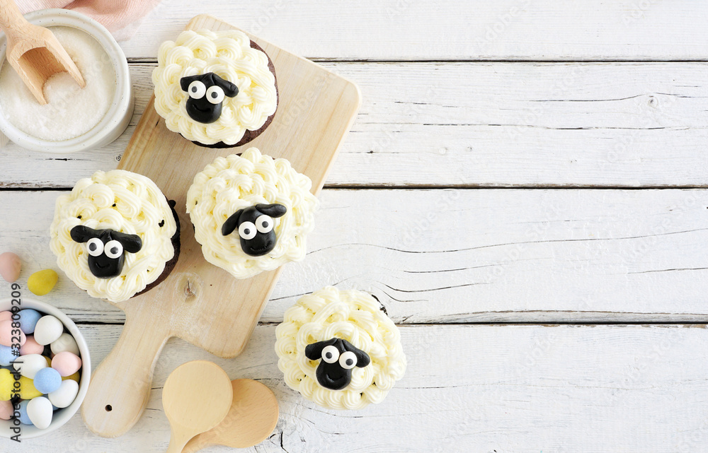 Poster cute easter sheep cupcakes. above view table scene with a white wood background and copy space.