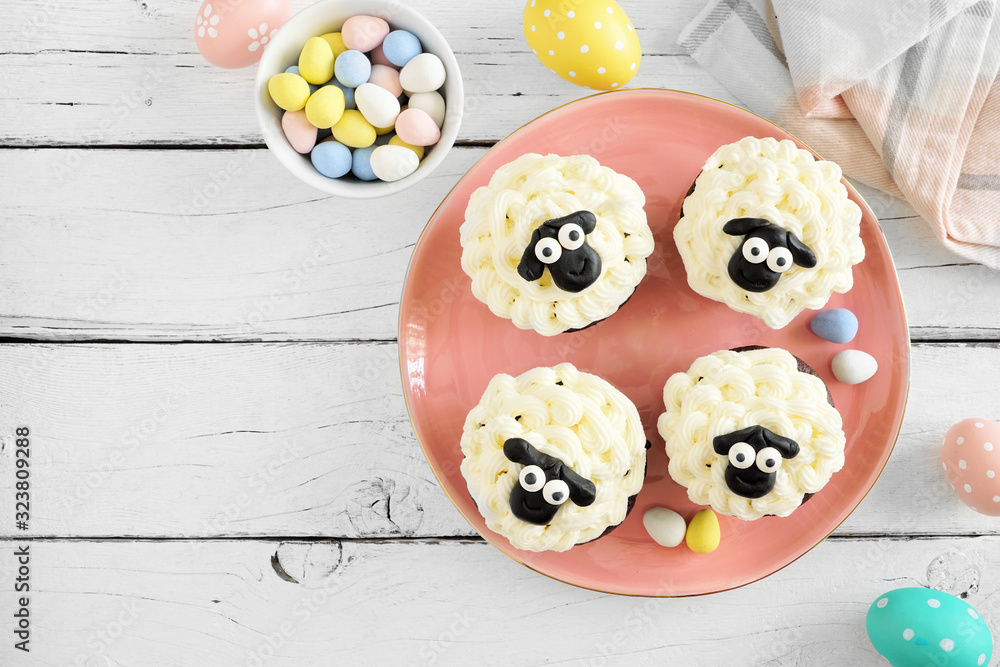 Aufkleber cute easter sheep cupcakes. above view table scene with a white wood background.