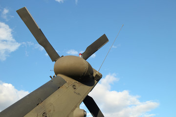tail boom and rotor with rear propeller blades on back of military helicopter against blue sky...