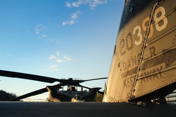 rear view of the tail of a military helicopter and main rotor propeller blades against a blue sky...