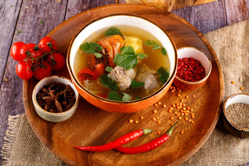 Uzbek shurpa soup in a bowl with two hot peppers
