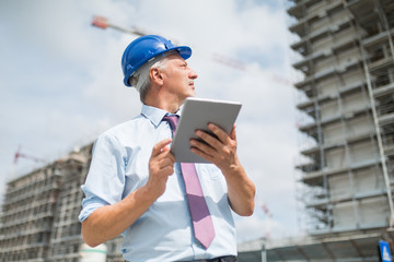 Architect using his tablet in front of a construction site