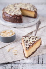 Obraz na płótnie Canvas Piece Slice of Сheesecake with Chocolate, Caramel, Peanut Paste, Nougat Layered Cake on white table background