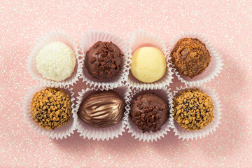 A variety of chocolates in corrugated paper cups top view, sweets with different fillings, nut and coconut sweets with crunchy crumbs