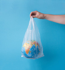 no plastic concept. hands holding planet earth in plastic bag.