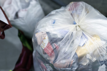 Close-up tied full household plastic waste bag filled with non-recyclable rubbish at recycling...