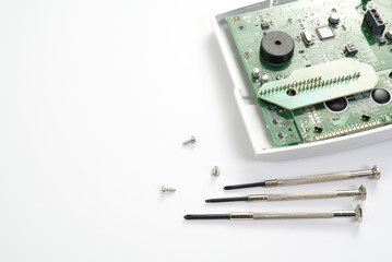 Home alarm control panel repairing. Open Electronic board panel with screwdrivers on a white background.