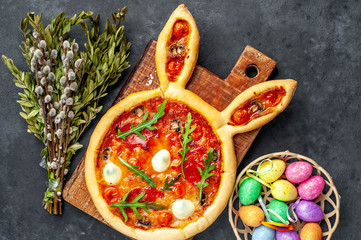 Festive Easter pizza in the form of a rabbit with eggs, colorful  Easter eggs and willow on a stone...