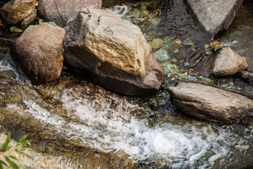 Naklejka premium water flows over stones. Beautiful mountain waterfall in the forest. 