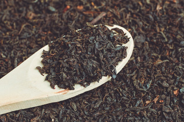 Wooden spoon on dry black tea. The concept of the distribution of tea by volume.
